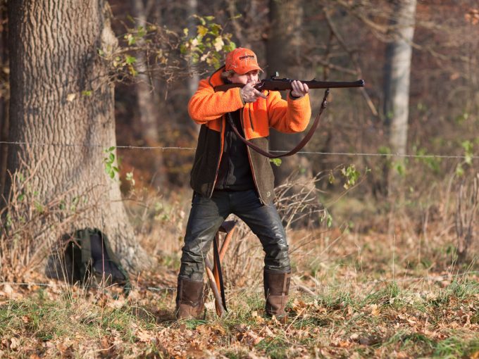 Ein Jäger, der auf der Drückjagd ist, zielt mit seiner Waffe. 