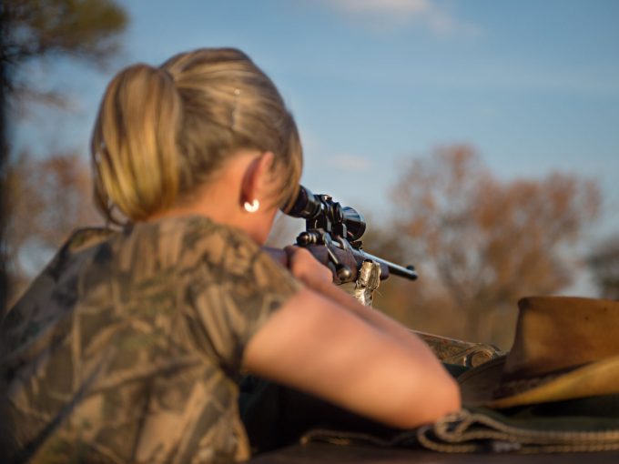 Eine Jägerin zielt mit ihrer Waffe auf ein Ziel in der Ferne. 