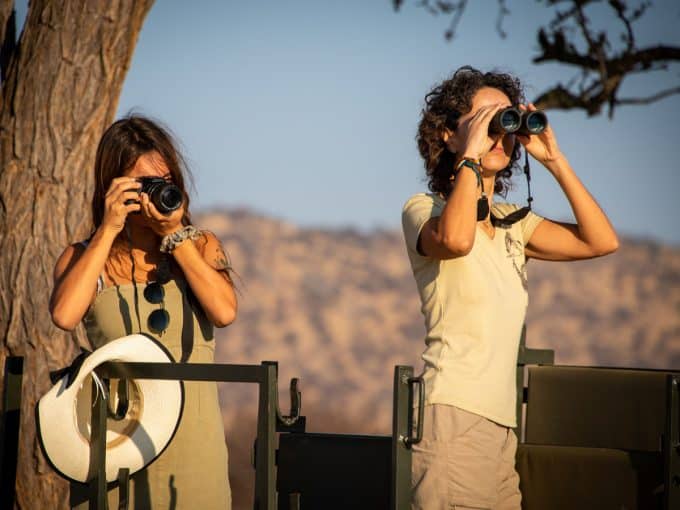 Eine Frau beobachtet die Natur mit ihrem Fernglas, die andere Frau fotografiert die Landschaft.