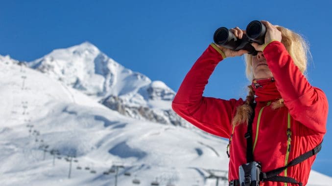 fernglas-ratgeber-skiurlaub-skifahrerin-auf-berg-mit-fernglas